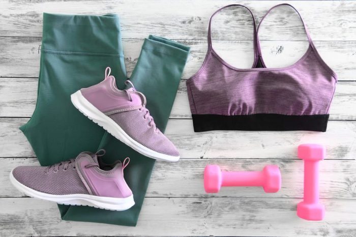 Womens active clothes (leggings, bra) footwear (sneakers) and equipment (pink dumbbells). Active lifestyle concept, Flat lay