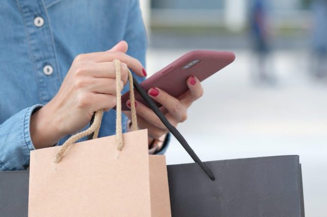 Woman use of mobile phone for shopping with holding shopping bag 