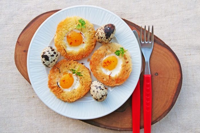 Egg in a basket with quail eggs and saffron on white plate top view