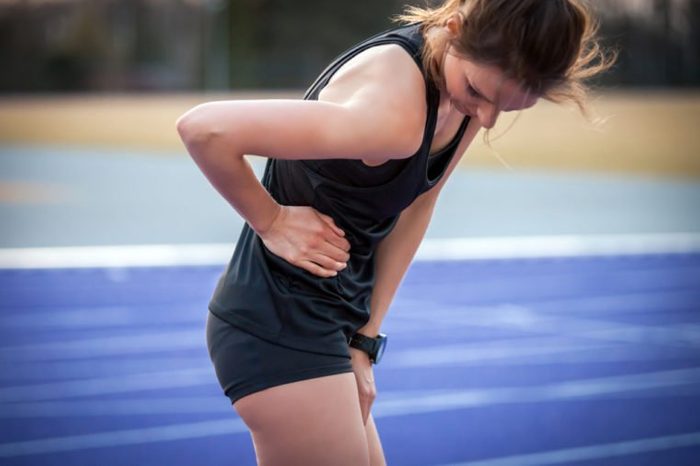 Athlete woman has side crumps, pain during running training