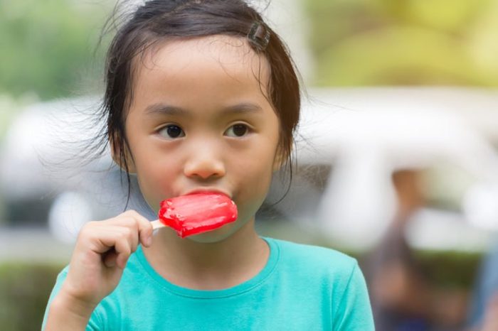 asian child eat red ice cream bar