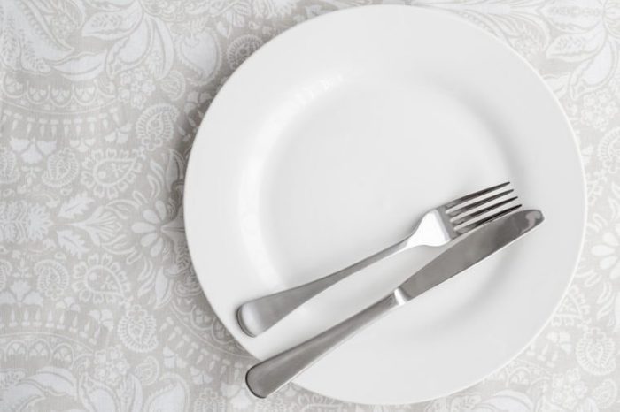 Knife and fork on white plate - top view photo