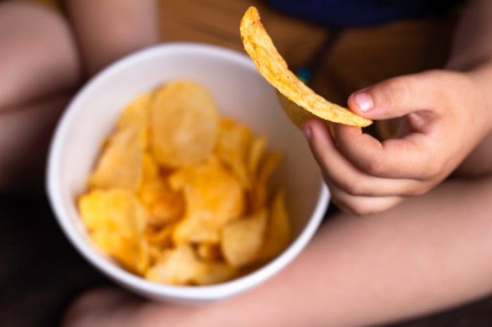 child's hand holds potato chips, concept of harmful food, fast food, obesity