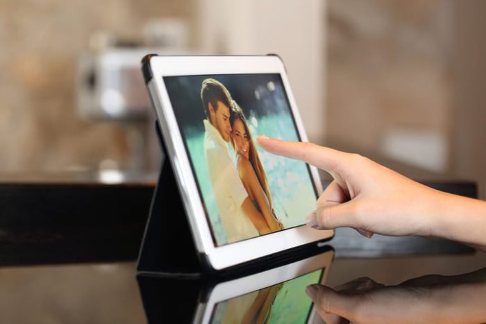 Woman hand using a tablet watching photos and touching screen at home