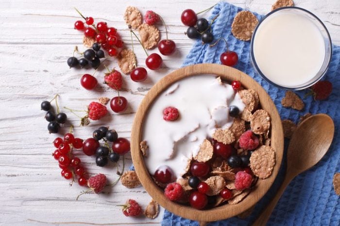 cereal with milk and fresh berries in a wooden bowl. horizontal view from above 