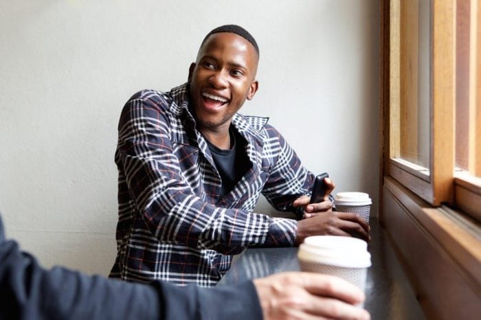 Portrait of smiling young african man sitting at cafe with a friend