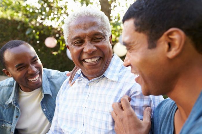 Senior man talking with his adult sons in garden, close up
