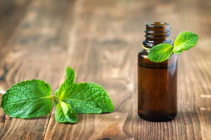 Peppermint essential oil in a glass bottle with a tag on wooden background