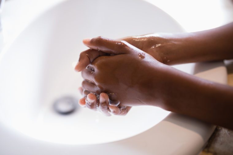 Cropped image of person washing hands at sink in bathroom