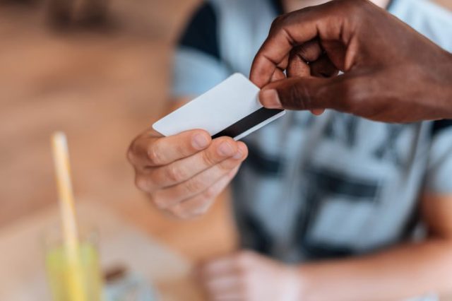 cropped view of african american waiter taking payment with credit card in cafe 
