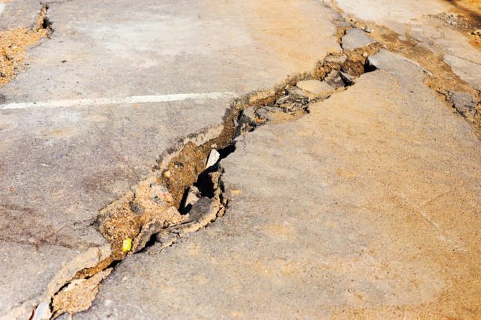 Huge cracks on pavement due to natural disasters, landslide, earthquake. Broken coating of asphalt leading to pothole, dangerous for vehicles pedestrians. Of poor road emergency situations