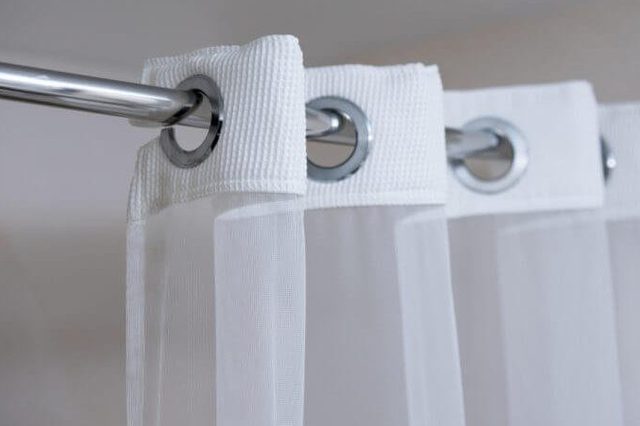 Shower curtain hanging from a chrome shower curtain rod