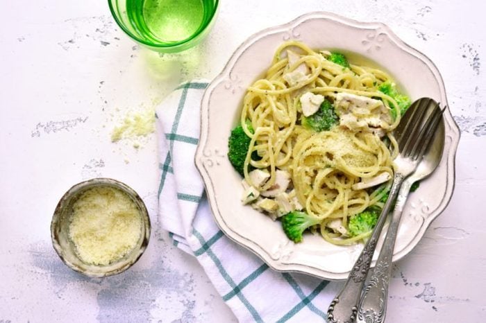Spaghetti with broccoli,chicken fillet and parmesan in a vintage white bowl on a light background.