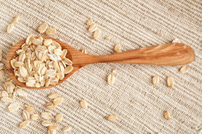 Oatmeal flakes and wooden spoon on fabric