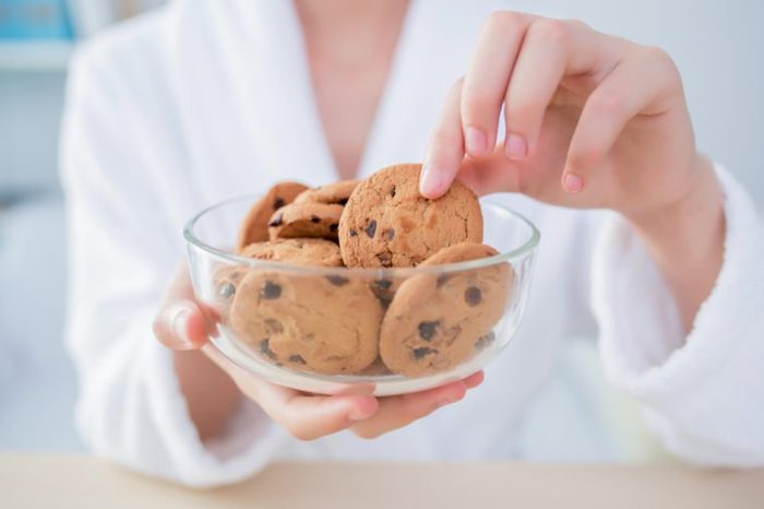 Woman eating cookie at home