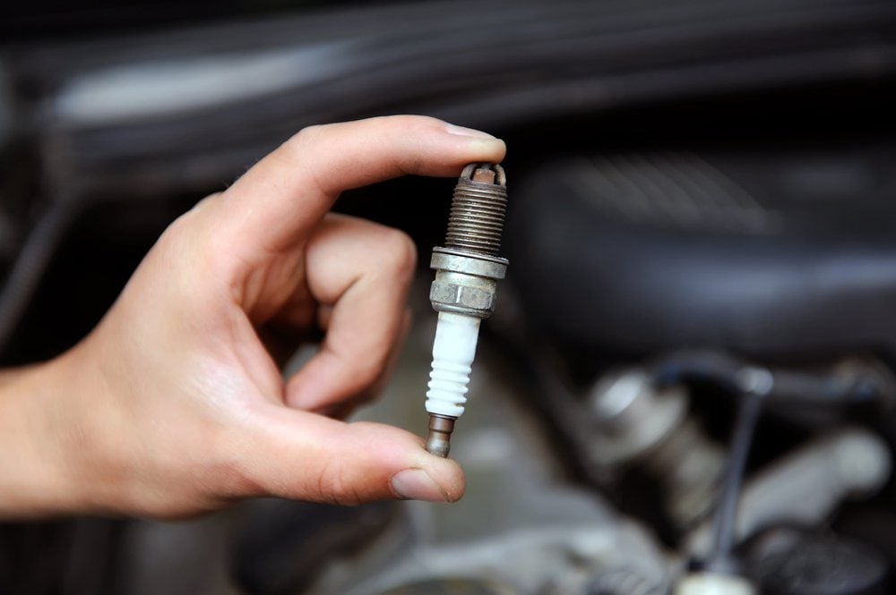 Auto mechanic holds an old spark plug