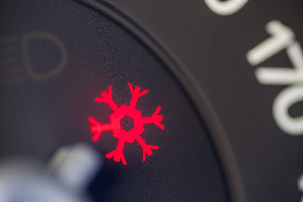 Color close up image of a car's snow warning symbol lighting up on the dashboard.