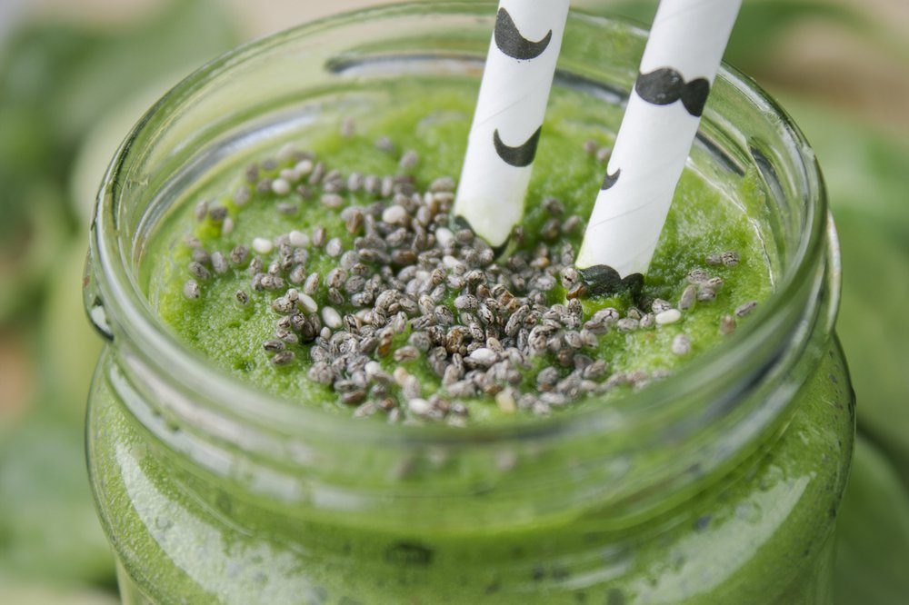 Green smoothie with spinach and kale, kiwi and lime topped with chia seeds.