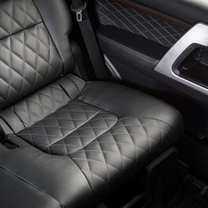 Back passenger seats in modern luxury car, frontal view, perforated black leather with stitching