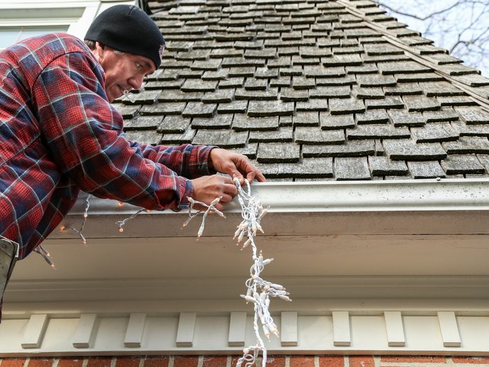 Man putting Christmas lights on roof