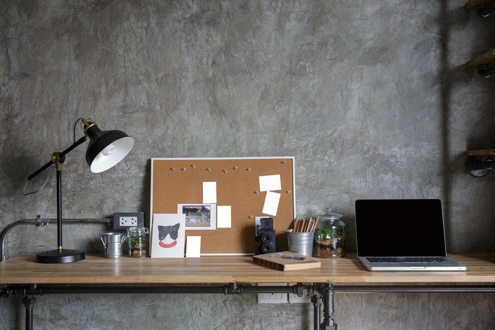 Home office interior in loft space with wooden table, office supplies, documents, notebook and laptop,