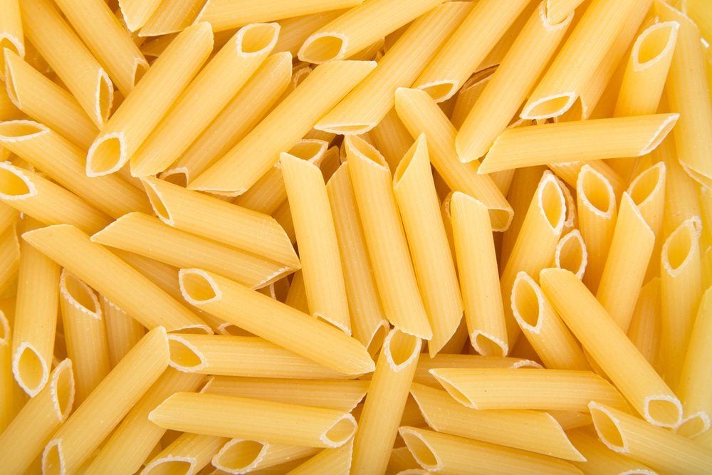 Image in close-up of raw penne pasta.