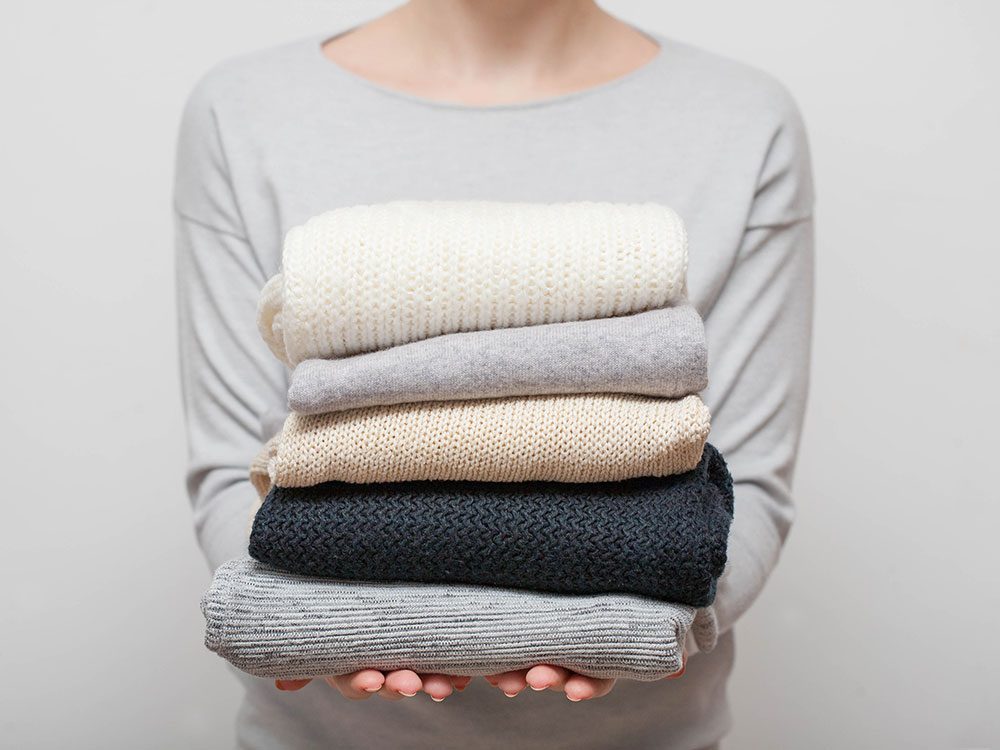 Woman holding a stack of folded sweaters