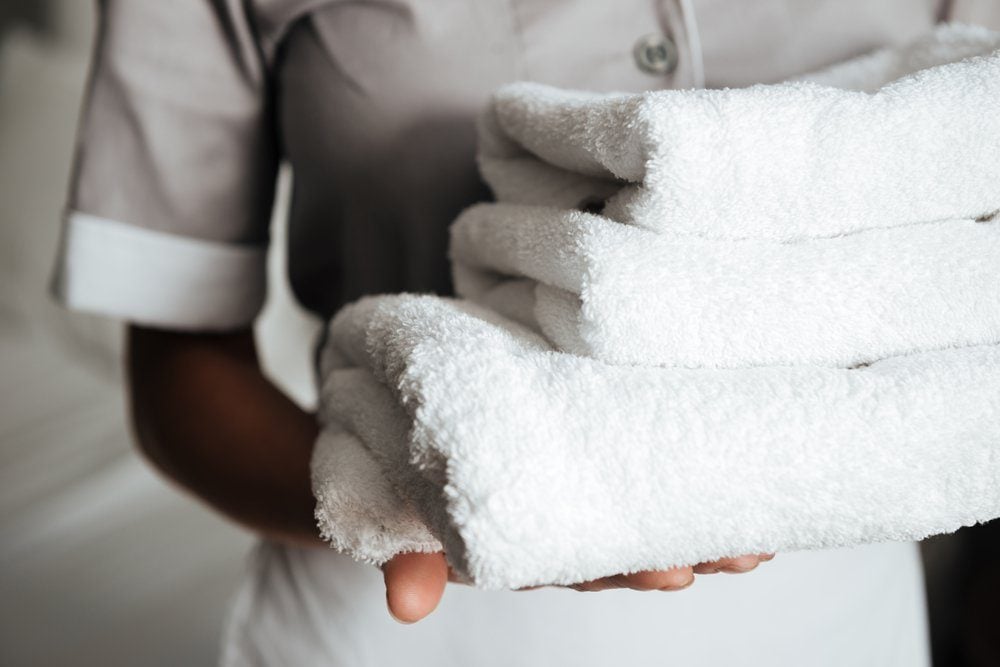 Close up of a young hotel maid holding clean folded towels
