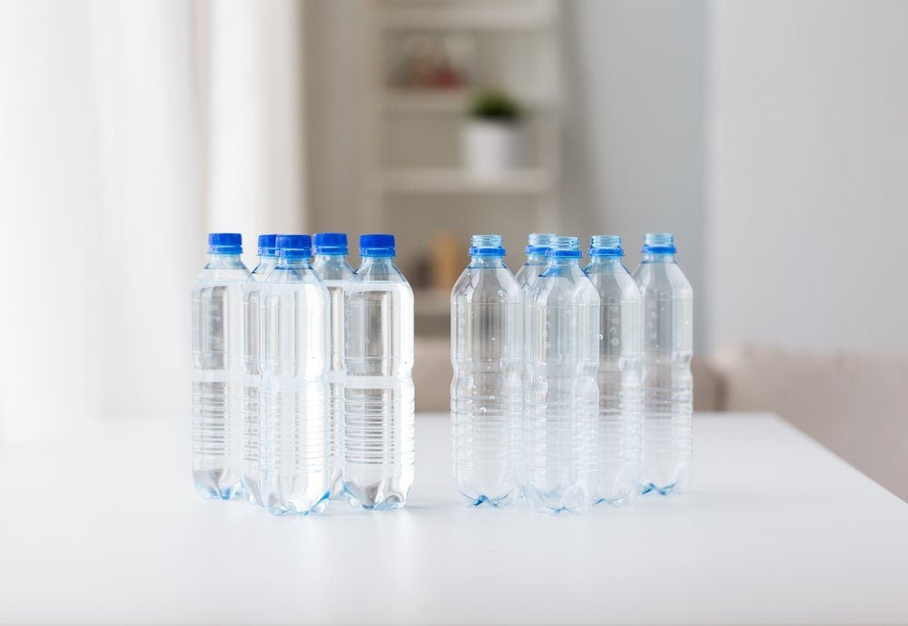 recycling, healthy eating and food storage concept - close up of plastic bottles with pure drinking water on table