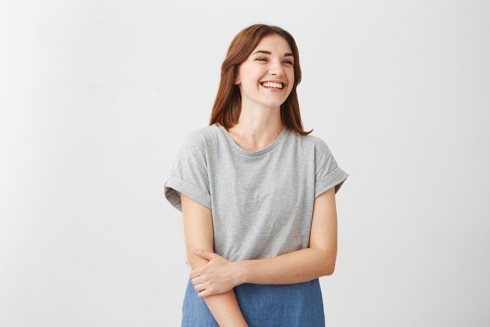 Portrait of sincere young happy cheerful girl smiling laughing over white background.