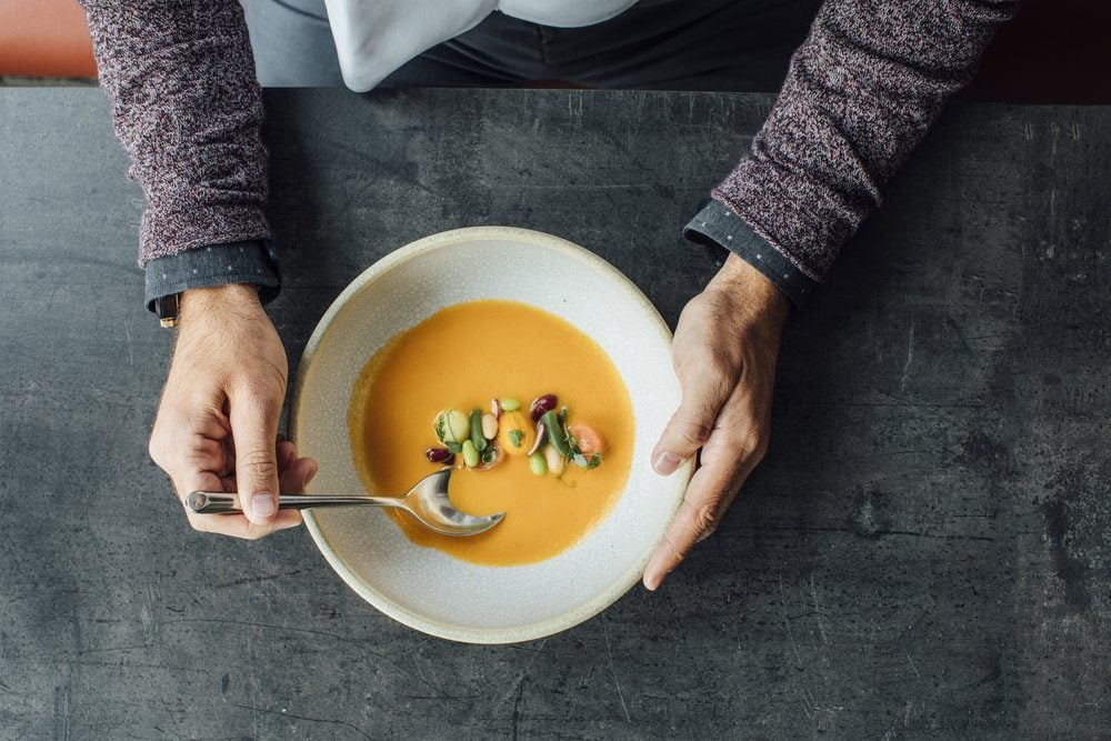 Hands of unrecognisable man eating a soup at restaurant.