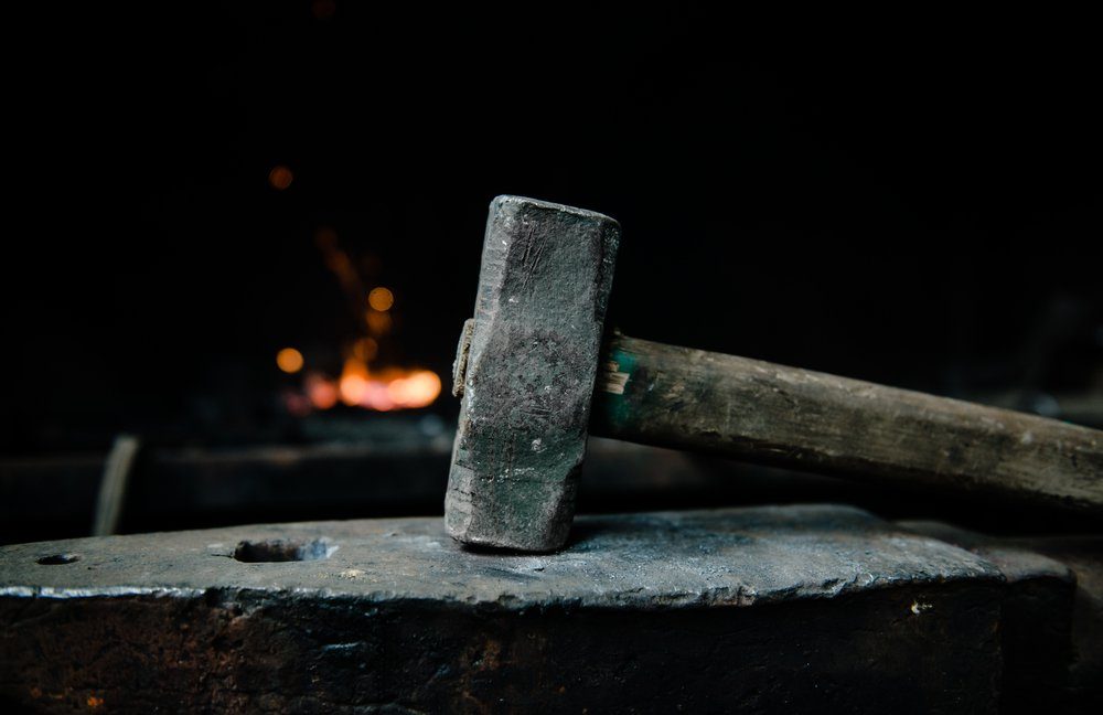 blacksmith hammer on the anvil against the background of fire