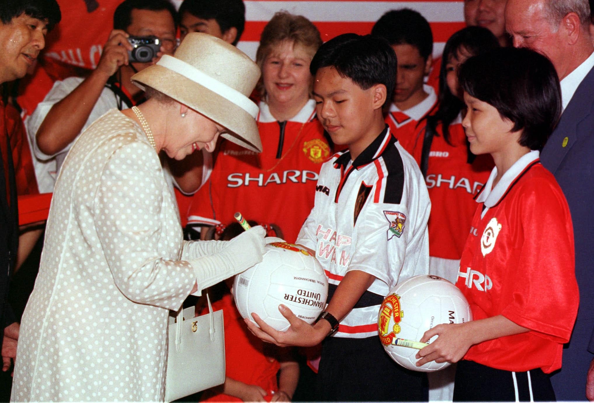 Queen Elizabeth Signs A Manchester United Football For The Mayalsian Branch Of The Manchester United Supporters Club In Kuala Lumpur Malaysia. 1998 . Rexmailpix.