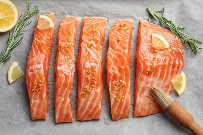 Fresh salmon with mustard on parchment, top view