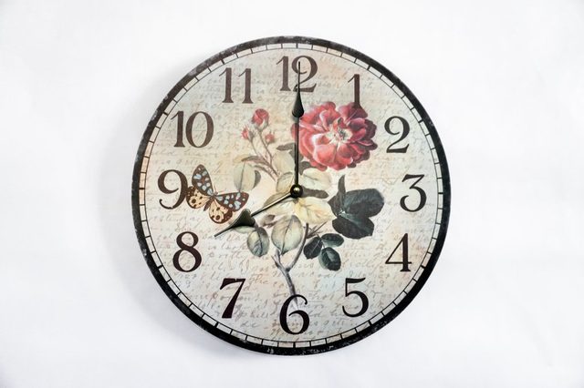 Vintage clock hanging on white wall shows eight oclock