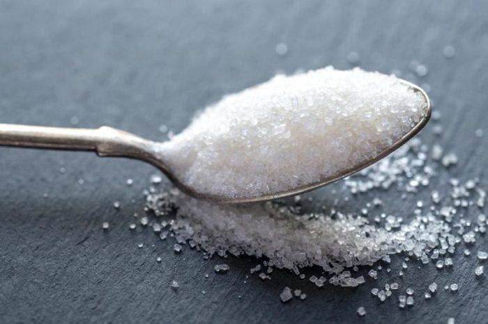 Spoon with white sugar on the dark background