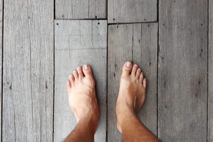 Man's bare feet on a natural wood floor