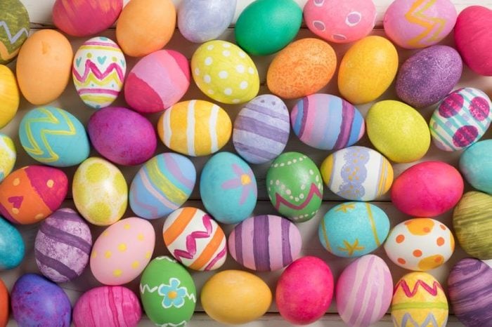 Many Bright and Colorful Easter Eggs Filling the Background. They are hand-painted or dyed. It's a closeup, or macro, with a horizontal top view in flat lay style that can be used vertical.