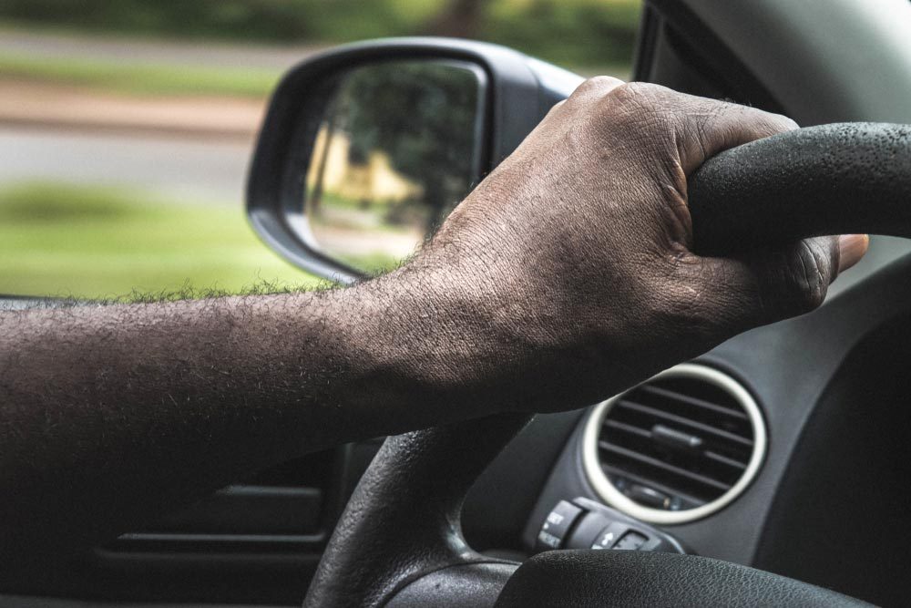 African Male hands on the steering wheel of a car while driving.Driver holding steering wheel. Black Man hands holding a steering wheel confidently. Hands on wheel - Man driving car - Africa