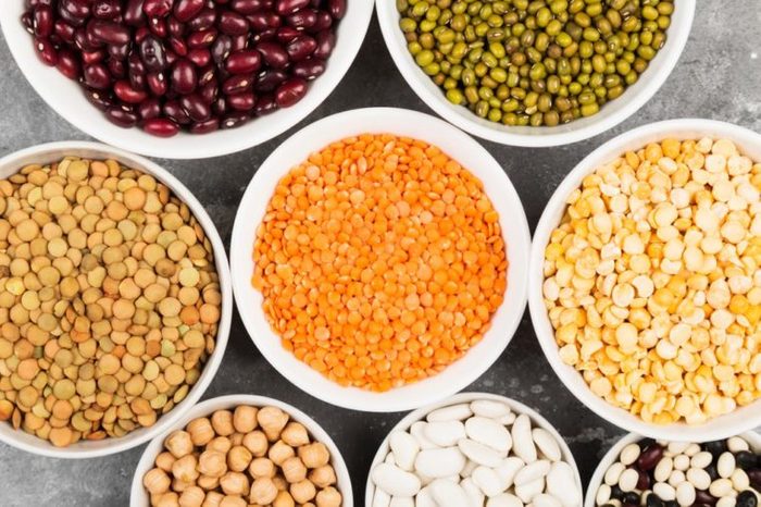 Assortment of beans (red lentil, green lentil, chickpea, peas, red beans, white beans, mix beans, mung bean) on gray background. Top view. Food background