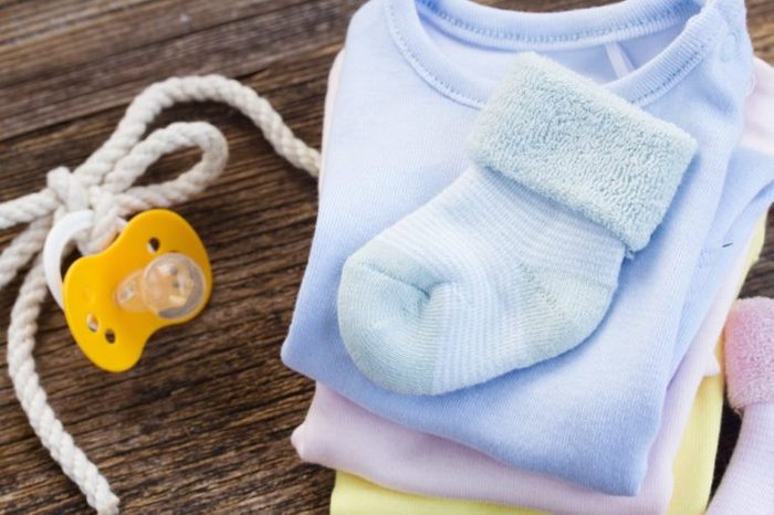 newborn baby clothes and blue socks on wooden background