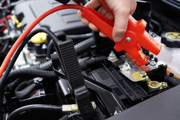 Close-Up Of Mechanic Attaching Jumper Cables To Car Battery