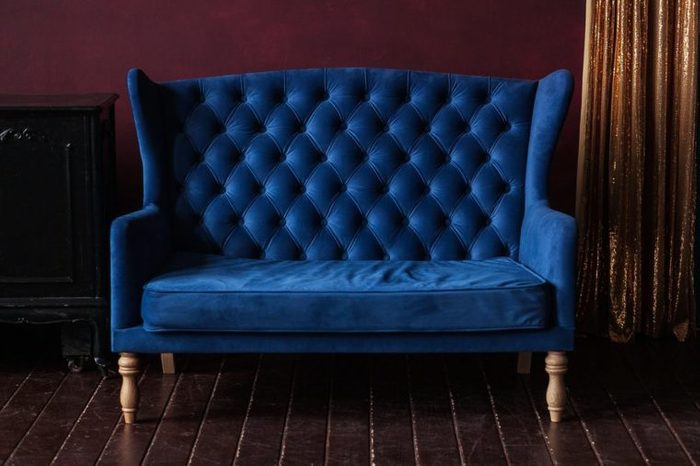 Marsala wall, golden curtain and vintage upholstered blue sofa