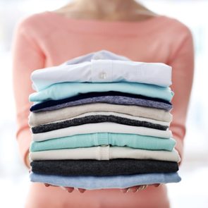 Woman holding folded pile of clothes
