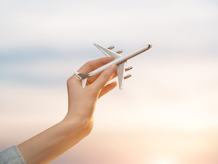 Booking vacation online - woman holding model airplane