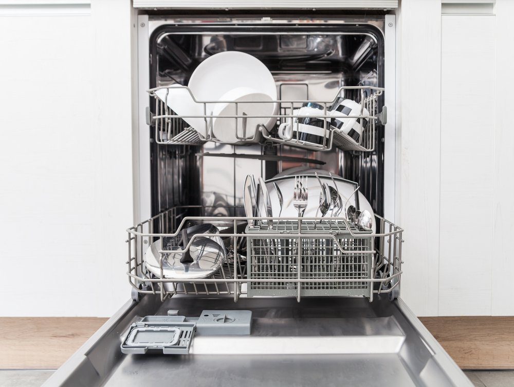 Open dishwasher with clean dishes in white kitchen, front view
