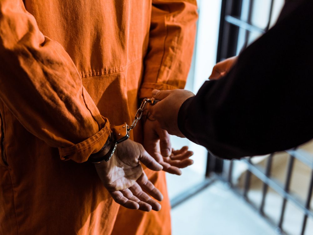 Prisoner being handcuffs in orange jumpsuit