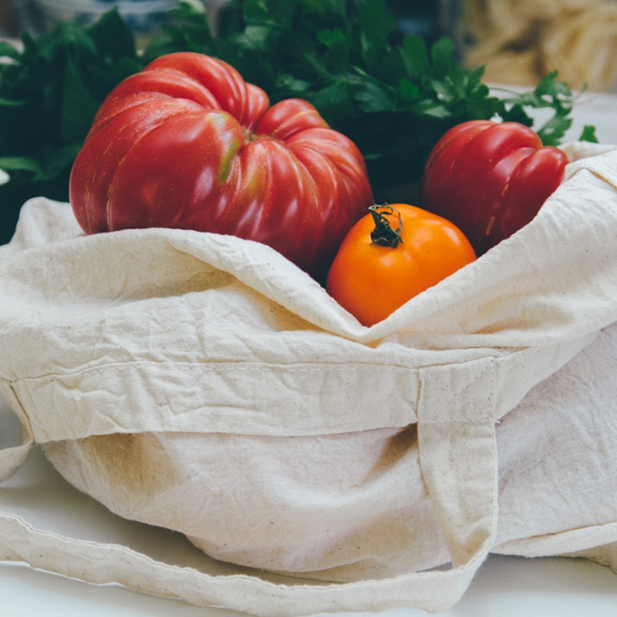 Reusable canvas grocery bag with red and yellow tomatoes and spinach.