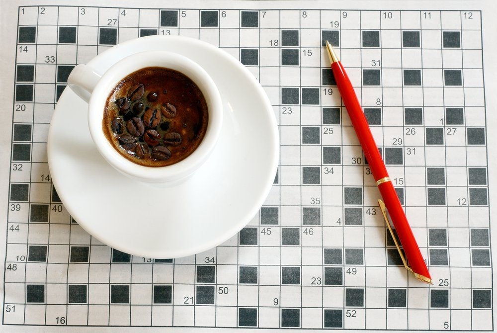 a cup of coffee with crossword in background
