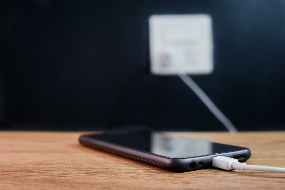 Mobile smart phones Black charging on wooden